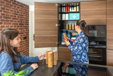 Anne ve kız acil durum kilerine su, konserve yiyecek ve ilk yardım çantası da dahil olmak üzere kurabiye paketleri ekliyor. Doğal afet ya da elektrik kesintisi için 72 saat hayatta kalma kiti hazırlayan aile.