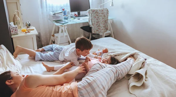 Avslappnad mor och söner leker över sängen — Stockfoto