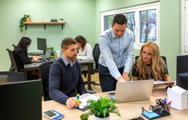 Bir proje üzerinde birlikte çalışan, verileri analiz eden ve çağdaş bir çalışma alanında verimli bir ekip toplantısı sırasında büyüme ve başarı stratejilerini tartışan çeşitli iş adamları