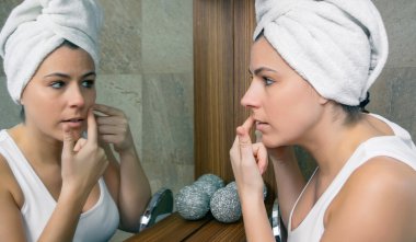 Genç kadın aynada bir akne sivilce sıkma