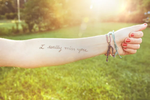 Kvinnliga arm med text - jag verkligen saknar dig - skriven i huden — Stockfoto