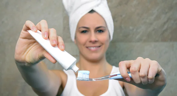 Woman hands holding toothbrush and placing toothpaste on it — Stock Photo, Image