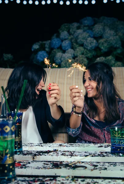 Mulheres felizes casal segurando sparklers em uma festa — Fotografia de Stock