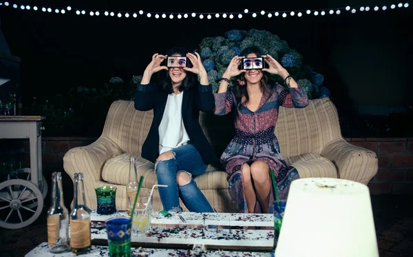 Mujeres jóvenes graciosas sosteniendo teléfonos inteligentes que muestran los ojos masculinos — Foto de Stock