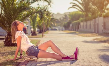 Kaykay açık havada yaz üzerinde oturan ile genç kız