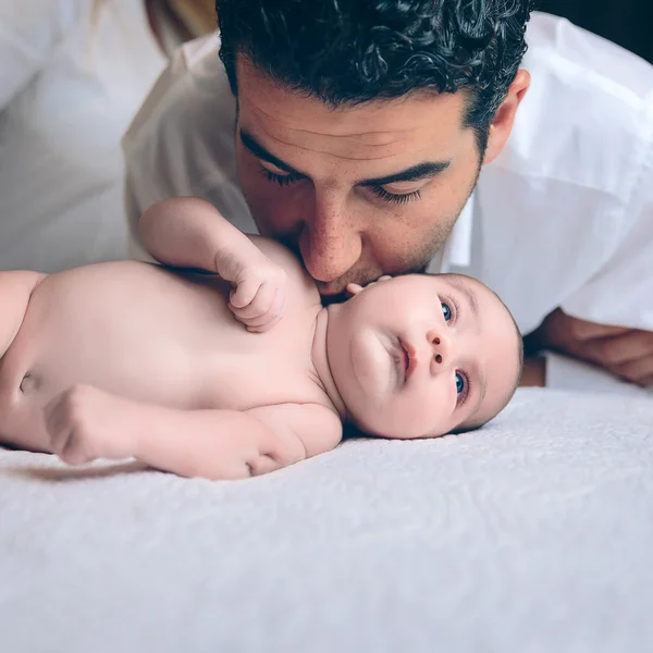 Homem beijando a pacífica recém-nascido deitado sobre a cama — Fotografia de Stock