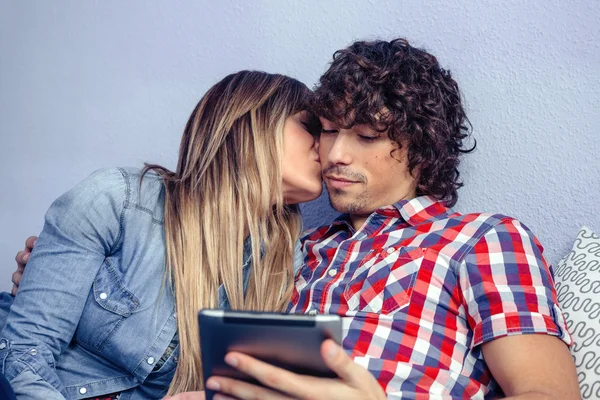 Bela jovem mulher beijando para homem olhando tablet — Fotografia de Stock