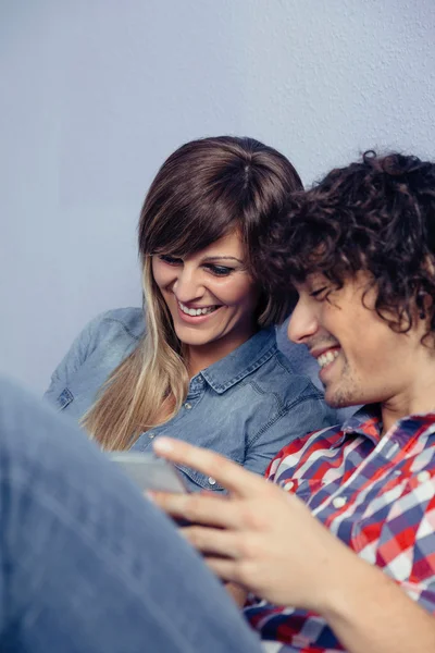 Casal apaixonado procurando smartphones e rindo — Fotografia de Stock