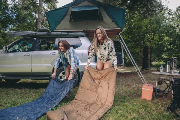 Junge Frauen legen Schlafsäcke über das Gras — Stockfoto