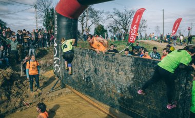 Runners climbing wall in a test of extreme obstacle race