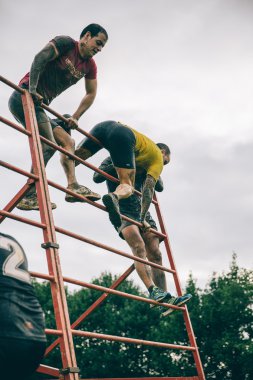 Runners climbing structure in a test of extreme obstacle race