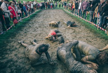 Runner trying to help woman crawling under electrified mesh in a test of extreme obstacle race