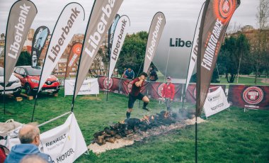 Runner jumping over burning logs in a test of extreme obstacle race