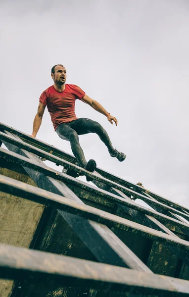 Runner going down wall in a test of extreme obstacle race — Stockfoto