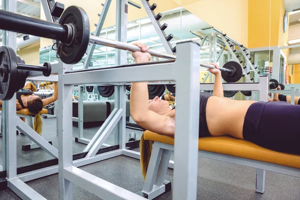 Mujer con barra en un entrenamiento de press de banca —  Fotos de Stock