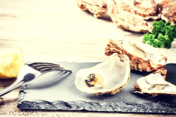 Verse oesters met citroen op stenen plaat — Stockfoto