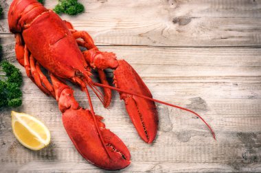 Steamed lobster with lemon on wooden background clipart
