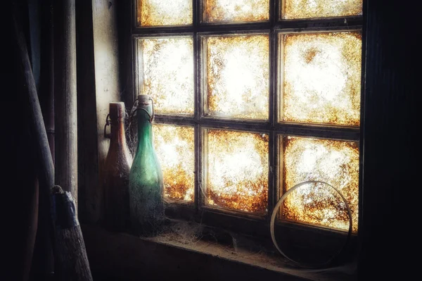 Velha janela suja com garrafas empoeiradas — Fotografia de Stock