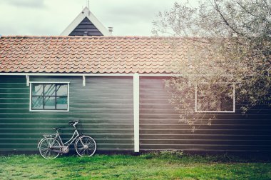 Old bicycle leaning against wooden barn clipart