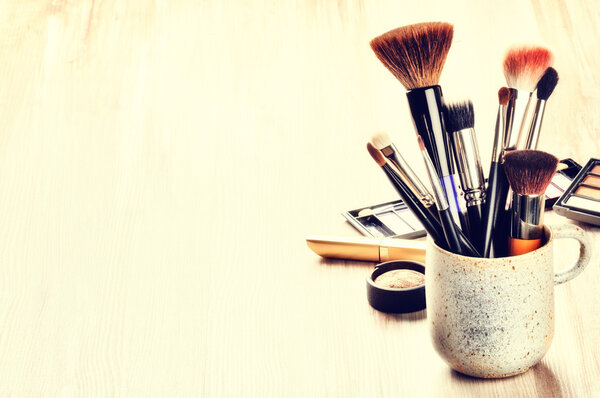Various makeup brushes on light background