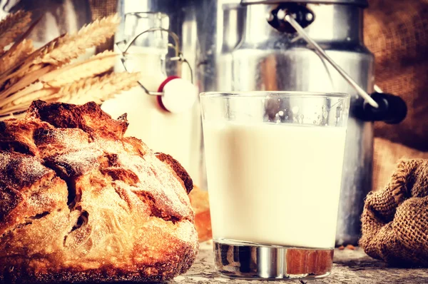 Glass of milk and bread in country setting — Stock Photo, Image