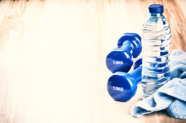 Концепция фитнеса с гантелями и бутылкой воды — стоковое фото