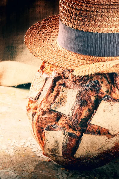 Freshly baked bread loaf with straw hat — Stock Photo, Image