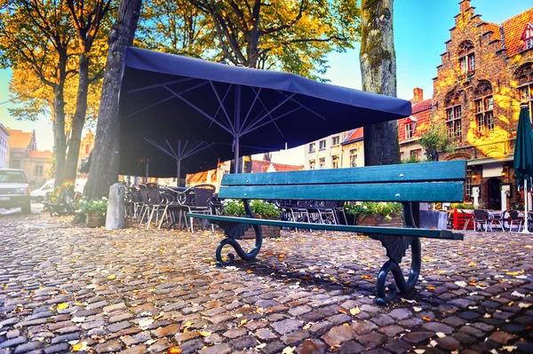Одинокая скамейка и кафе на открытом воздухе — стоковое фото