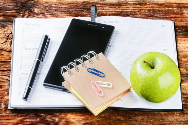 Bureau avec agenda papier, smartphone et pomme verte — Photo