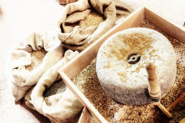 Antigua piedra de molino con granos de trigo — Foto de Stock