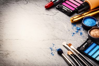 Various makeup products on dark background clipart