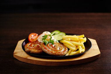 Ahşap masa üzerinde bir tavada kızarmış sosis