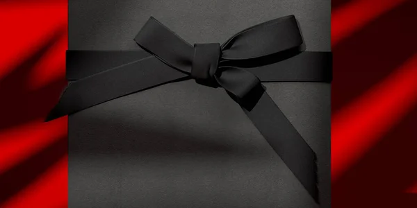 Пустая подарочная коробка с бантом для праздников, празднования и продажи концепции. Черный подарочный коробок с черной лентой бант на красном фоне. 3d-рендеринг. — стоковое фото