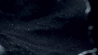 Bitcoin madencilik konsepti. Siyah kumun kalınlığından yükselen ve parlayan bir altın sikke. Yüksek derinlikte alan videosu.