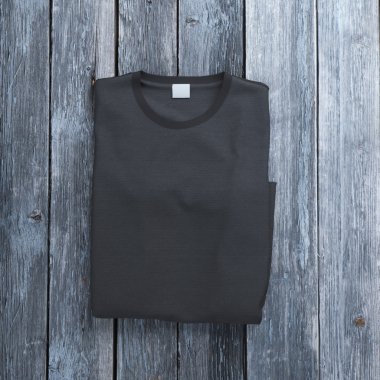 Siyah t-shirt ahşap arka plan üzerinde katlanmış.