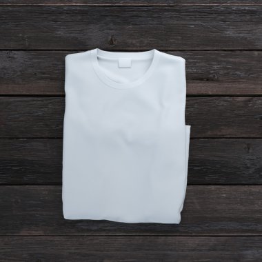 Beyaz t-shirt ahşap arka plan üzerinde katlanmış.