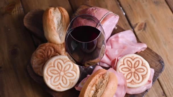 Um copo de vinho tinto, mortadela, tijel e pães diferentes em uma mesa de madeira. Uma partida tradicional pré-jantar na região norte da Itália, na Emília Romanha. Vídeo vertical para smartphones. — Vídeo de Stock