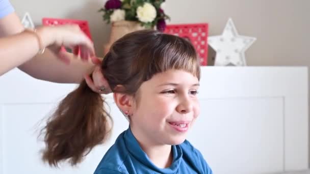 A mãe corta a franja das filhas no quarto na cama. Pequena menina feliz em casa no quarto fazendo um corte de cabelo. — Vídeo de Stock