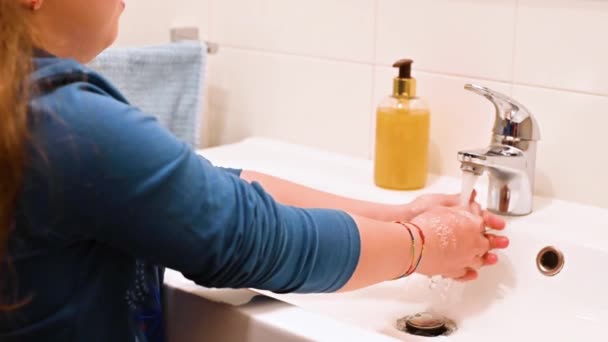 A gyerek szappannal mossa a kezét a fürdőszobában. A kislány betartja a higiéniát és vigyáz magára. A megfázás és a vírusok elleni szükséges intézkedések. — Stock videók