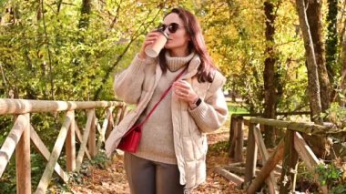 Çevre koruma programında maskeli ve kahveli bir kız sonbahar parkında dinleniyor. Dışarıda kahvesi olan genç bir kadın..