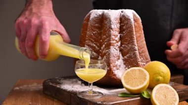 Bir adam elinde bardakla limoncello tutuyor. Krema şekerli, yıldız şeklinde bir makarna.