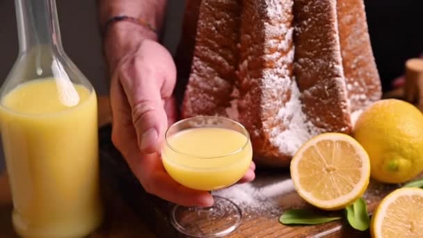 Un hombre sostiene un limoncello con un vaso en las manos. Pastas blandas en forma de estrella espolvoreadas con azúcar glas — Vídeo de stock