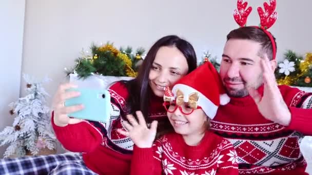 幸せな家族、お母さん、お父さんと娘はクリスマスにビデオ通信について話しています。2021年に自宅で新年を祝う。隔離期間中のオンラインお祝い. — ストック動画