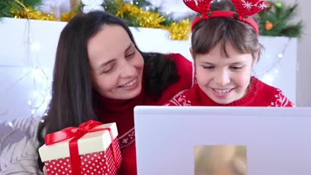 Mutter und kleine Tochter bestellen Weihnachtsgeschenke online. Glückliche Familie mit Laptop kauft von zu Hause aus per Computer ein. Frohes neues Jahr. — Stockvideo