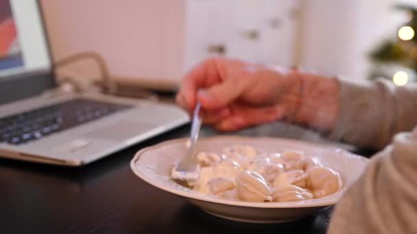Yalnız Adam ekşi kremalı hamur tatlısı yiyor ve internetten bilgisayara bakıyor. Rusya 'da sıkıcı Noel ve Yeni Yıl. — Stok video