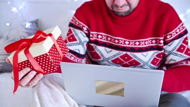 Kırmızı Noel kazağı giyen bir adam evden sürpriz internet siparişi veriyor. İnternetten noel hediyesi almak - online alışveriş konsepti. Yeni yıl tatili konsepti. Dikey video. 4k görüntü — Stok video