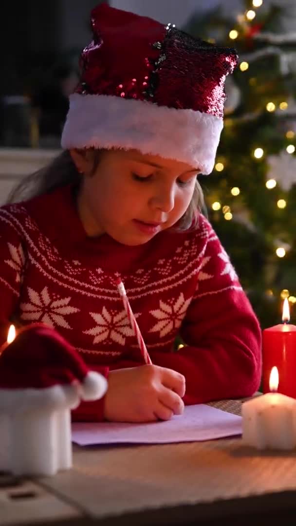 Petite fille écrivant une lettre au Père Noël claus dans une maison douce décorée pour Noël. — Video