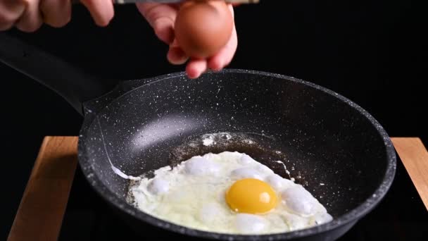 Gebratene Eier in einer Pfanne. Das Ei wird in Butter gebraten und die Frau bricht das zweite. Traditionelles Frühstück. — Stockvideo