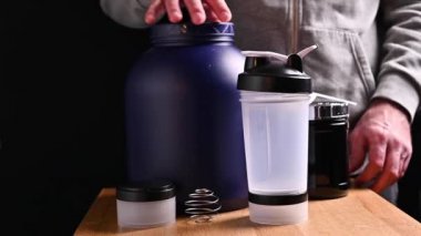 Bir sporcu bir spor kokteyli hazırlar. Masanın üzerinde süt proteini ve takviye paketleri var. Fitness, vücut geliştirme, sağlıklı yaşam tarzı konsepti.