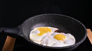 Kızartma tavasında yumurta. Yumurta tereyağında kızarır ve kadın ikincisini kırar. Geleneksel kahvaltı.